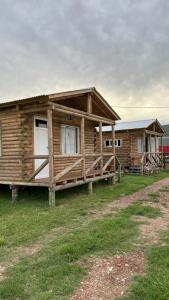 a log cabin with a porch and a house at Cabañas La Silvanita in Balcarce