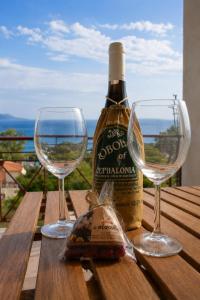 a bottle of wine and two wine glasses on a table at Elichri Theros Studios in Katelios