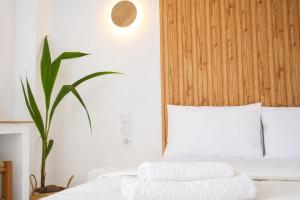 a bedroom with a bed with white sheets and a plant at Elichri Theros Studios in Katelios