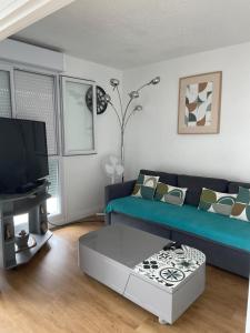 a living room with a blue couch and a tv at appartement mérignac avec parking in Mérignac