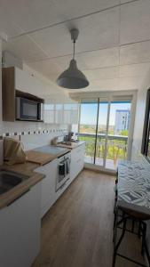 a kitchen with white cabinets and a table and a window at appartement mérignac avec parking in Mérignac