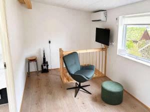 a room with a chair and a stool and a television at Hvanngarðs Smáttan by Stóra in Dalur