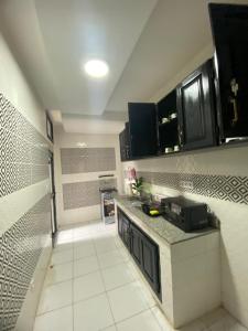 a kitchen with black cabinets and a white tile floor at Lita résidence in Yaoundé +7 photos