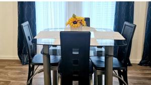 a glass table with chairs and a vase with a sunflower on it at Luxe Haven in Richmond