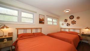 two beds in a bedroom with orange sheets at Nemandua Catskills: Hot Tub+Fire Pit+Pool Table+EV in Lanesville