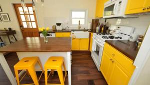 a kitchen with yellow cabinets and a counter with yellow stools at Nemandua Catskills: Hot Tub+Fire Pit+Pool Table+EV in Lanesville