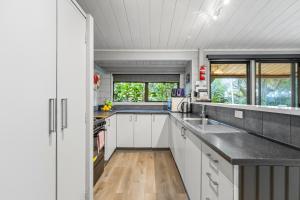 a kitchen with white cabinets and black counter tops at Orewa Motor Lodge in Orewa