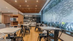 a restaurant with tables and chairs and a large window at Uniko Living Roma in Mexico City
