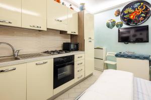 a kitchen with white cabinets and a sink and a microwave at Sea 150mt - Il Vicolo di Cetara in Cetara