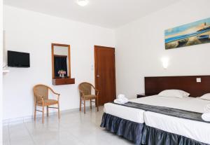 a bedroom with a bed and two chairs and a tv at Windmills Hotel Apartments in Protaras +36 photos