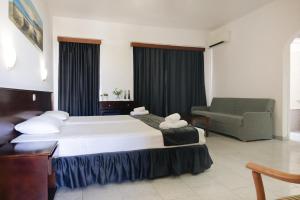 a hotel room with a large bed and a chair at Windmills Hotel Apartments in Protaras