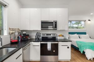 a kitchen with white cabinets and a sink and a bed at Irie Vibes Private Guest House Downtown in Raleigh