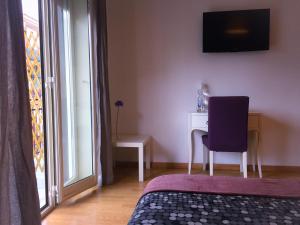 1 dormitorio con silla, escritorio y TV en Policlinico Apartments, en Catania