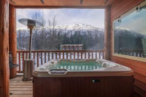 a jacuzzi tub on a deck with a window at 2 Bedroom Mountain View Condo with Private Hottub in Girdwood