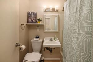 a bathroom with a sink and a toilet and a mirror at Spacious King Historic Art Deco Studio in Anchorage