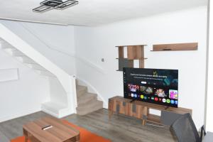 a living room with a flat screen tv and stairs at Magic House- London in Plumstead