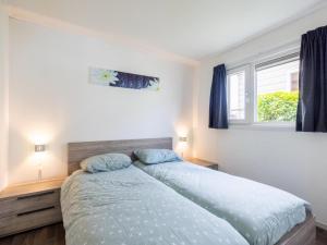 a bedroom with a bed with blue sheets and a window at Sluisje 55 in Kuinre
