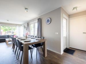 a dining room table with chairs and a clock on a wall at Sluisje 55 in Kuinre +17 photos