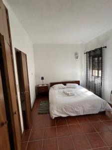 a bedroom with a white bed and a tiled floor at Casa dos Cândidos in Alagoa