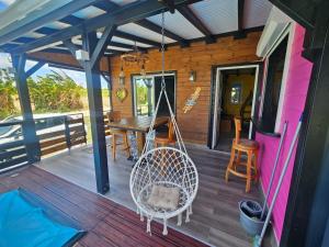 a porch with a swing and a table and chairs at Bungalow Sugarcane in Saint-Louis
