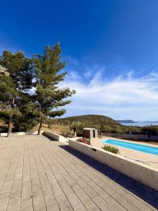 a swimming pool with a tree and a building at Domus Villa in Ermioni