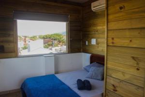 a small bedroom with a bed and a window at Take it Easy Hostel in Florianópolis