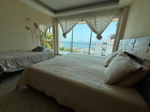 a bedroom with two beds and a large window at Casa las Palmas in Acapulco +35 photos