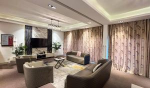 a living room with a couch and chairs and a television at Mac Residence in Lagos