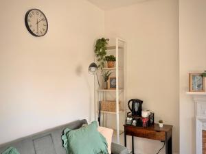 a living room with a couch and a clock on the wall at Central Reading Guest House in Reading
