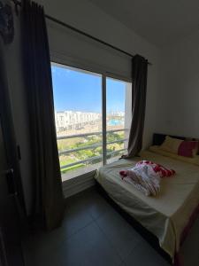 a bedroom with a bed and a large window at AMWAj in El Alamein