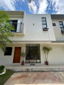 a white house with two potted plants in front of it at Residencia de Azucena in Tacloban