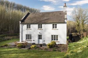 a white house with a picnic table in front of it at Roft Bank Cottage in Oswestry
