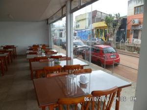 a restaurant with tables and chairs and a red car in the street at Hotel Status in Jaguarão