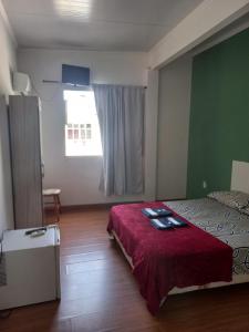 a bedroom with a bed with a red blanket and a window at Hotel Status in Jaguarão
