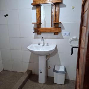 a bathroom with a sink and a mirror and a trash can at El Rincón de la Quebrada in Tilcara
