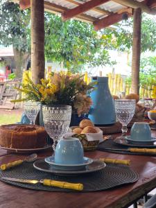 a wooden table with plates and cups and food on it at Portal Das Fadas - Hospedagem in Cavalcante +4 photos