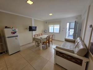 a living room with a couch and a table and a refrigerator at Departamentos Atlantic in Monte Hermoso