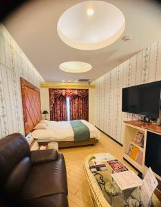 a bedroom with a bed and a couch and a tv at バリアンリゾート山口BarianResort Yamaguchi in Sanyoonoda
