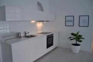 - une cuisine blanche avec un évier et une plante en pot dans l'établissement Charming Apartment 101, à Funchal