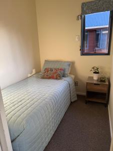 a small bedroom with a bed with a window at Alba Pacis in Paihia