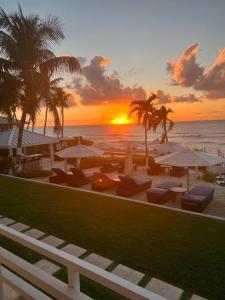 a sunset at a beach with chairs and umbrellas at Beachfront 3Br3Ba Skyyard Ocean Sunset Views, Pool in George Town