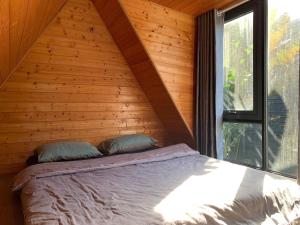 a bed in a wooden room with a window at Lang Omm in Tang Klang