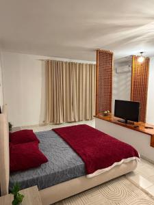 a bedroom with a bed with red sheets and a television at Villa Marsa in Dar el Haj Ahmed Souid