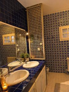 a bathroom with two sinks and a blue tiled wall at Villa Marsa in Dar el Haj Ahmed Souid +33 photos