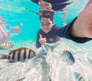 a man in the water with fish in the water at Antunes Beach Flats Paradise in Maragogi