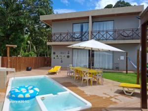 a house with a pool and a table and an umbrella at Antunes Beach Flats Paradise in Maragogi