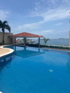 a large blue swimming pool with a gazebo at Casa las Palmas in Acapulco