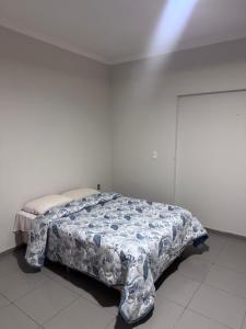 a bedroom with a bed with a blue and white comforter at Quarto privativo com suite para 1 pessoa in Campinas