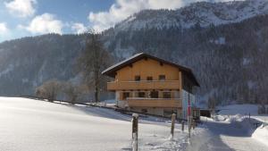 a building in the snow in front of a mountain at Haus Bilgeri in Nesselwängle