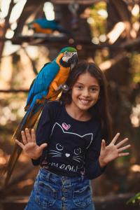 a little girl with a parrot on her shoulders at Portal Das Fadas - Hospedagem in Cavalcante